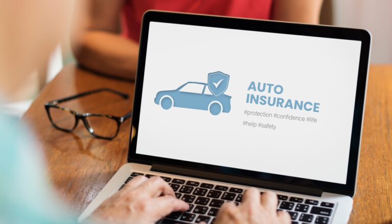 A person reviewing various auto insurance options on a laptop, surrounded by car-related documents and insurance brochures, symbolizing the process of choosing the best insurance deal.